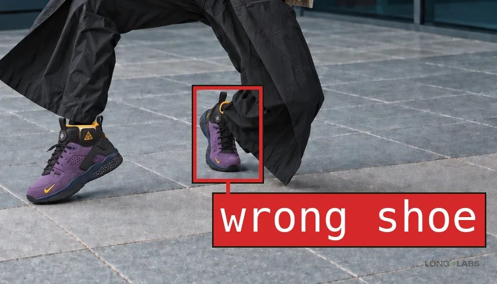 Generated photo of legs in wide black trousers mid-step on grey stone tiles, both in purple and black sneakers. A red box around the right foot is labelled wrong shoe.